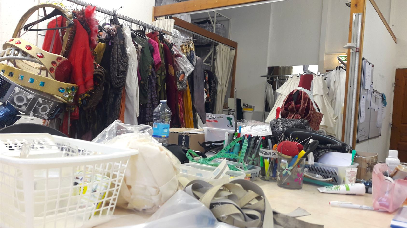 Vue de la table de l'atelier principal, avec pelotes d'épingle, ruban mesureur...