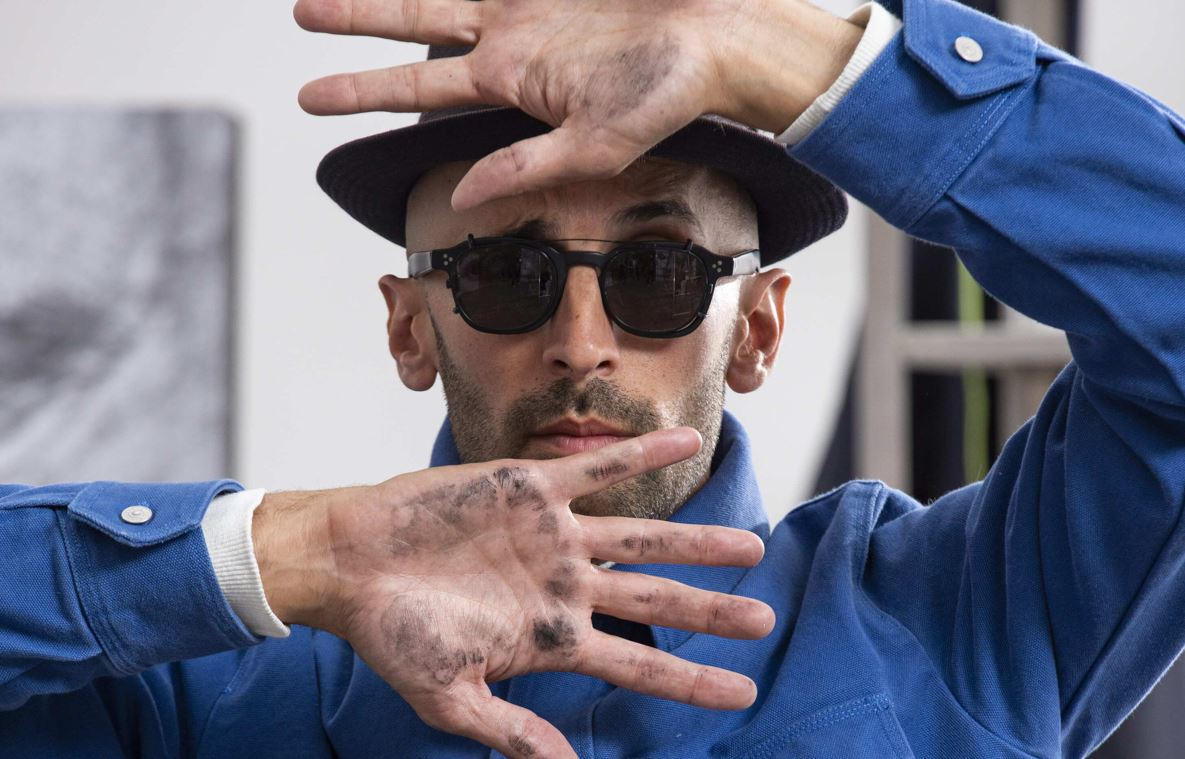L'artiste JR se cachant le visage entre les mains
