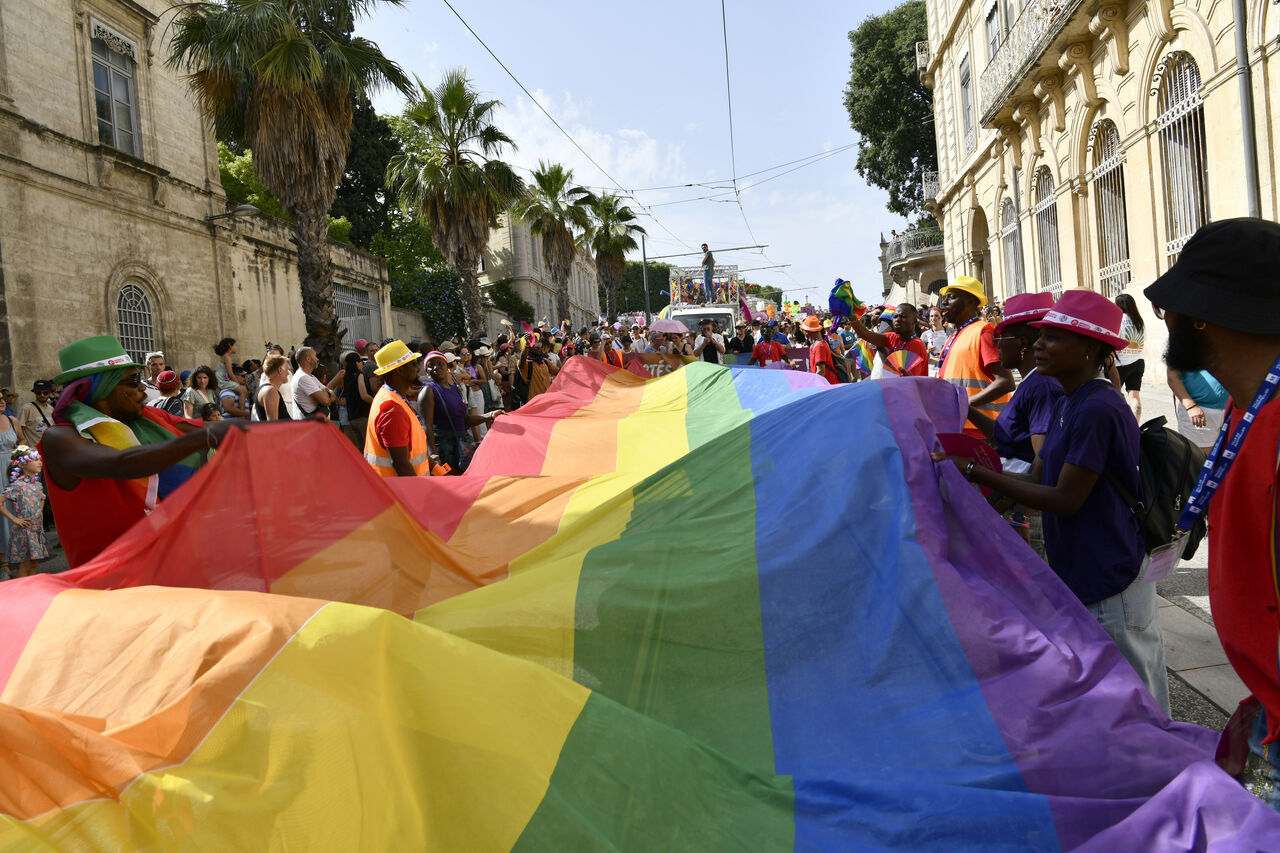 un immense drapeau arc en ciel déployé dans la rue 