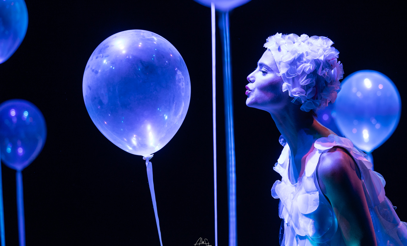Jeune femme en costume, soufflant sur un ballon