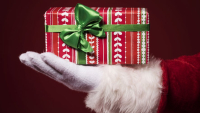 Visuel de main de père Noël tenant un paquet enrubanné